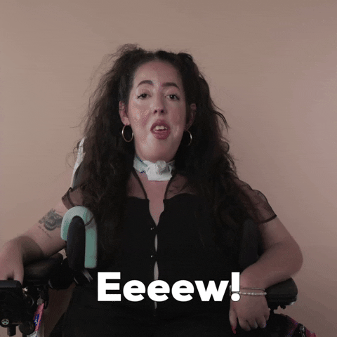 Reaction gif. A Disabled white woman with muscular dystrophy with wavy brown half up half down with two pigtails on top, seated in her motorized wheelchair, rolls her eyes dismissively and says, "Eeeew!"