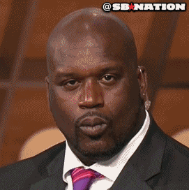 Sports gif. Dressed in a suit and staring straight at us, a flirtatious Shaquille O'Neal winks and kisses the air.