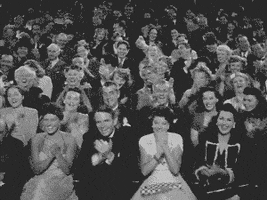 Video gif. Black-and-white footage of a well-dressed 1940s audience applauding with frame rate increased so they appear to clap at a superhuman speed.