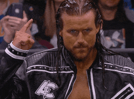 Sports gif. Wrestler Adam Cole wearing a leather jacket points up with his index finger then motions aggressively with his thumb as he mouths the word, "Move."
