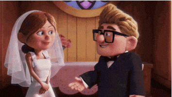 Disney gif. Carl and Ellie from Up are young and getting married. They've just said yes at the alter and Carl opens his arms to Ellie for the kiss. Ellie launches herself at him instead, giving him a big smooch that he looks happy and shocked at.