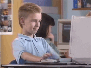 TV gif. A clip from a 90s Apple promo shows a young Brent Rambo sitting at a computer. He has a cool smirk and nods his head at the screen. The camera zooms in closer as he looks straight at us with a very serious look on his face, still nodding. He holds up a big thumbs up, giving a very serious, and somewhat awkward approval. 