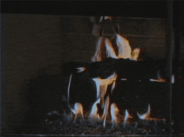 Video gif. Fire crackling over wood in a fireplace.