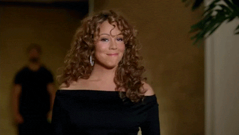 An animated gif of Mariah Carey blowing a little kiss and waiving goodbye before walking away.