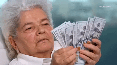 Video gif. A woman with short, gray hair fans out a stack bills as she counts them with a deadpan expression.