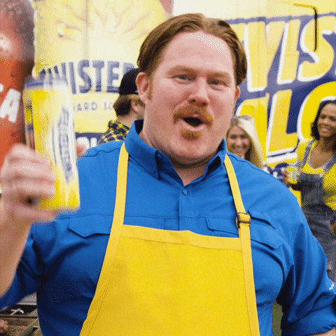 Ad gif. A man drinking a Twisted Tea stares and us and cheers, holding up his can. He smiles delightedly and looks pleased with his drink of choice. 