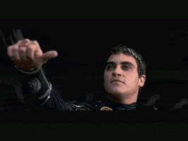Movie gif. Joaquin Phoenix as Commodus in The Gladiator with his arm out doing a sideways thumbs up. Surveying the scene for a moment, his expression becomes icy as he quickly points his thumb down.
