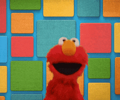 Cartoon gif. Elmo is doing his celebration dance, flapping his head side to side as he jumps with outstretched arms and a wide mouth. He stands in front of a colorful square background and his red coat is stark against the contrast of colors.