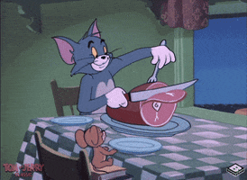 Cartoon gif. Tom and Jerry sit at a dining table as Tom cheerfully slices a piece of ham then puts it on Jerry's plate. Jerry leans forward in anticipation and smells it happily as Tom starts to cut another slice. 
