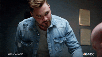 TV gif. Patrick Flueger as Adam Ruzek on Chicago PD lends forward to integrate a suspect. He has an angry expression on his face as he snaps his finger very close to the other man’s face.