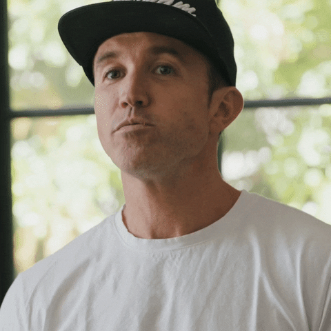 TV gif. Rob McElhenney, as himself in "Welcome to Wrexham," wears a black baseball hat and a white t-shirt. He tilts his head and his eyes go wide as he mouths the word, "wow."
