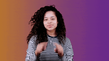 Celebrity gif. Ella Mai, an English musician, draws an air heart that has been edited to have a red heart coming out of her fingers.