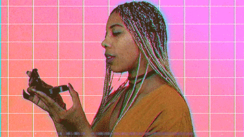 Video gif. Against a tiled light purple to orange gradient background, a woman with long, braided hair shuts her blush kit and winks at us while saying, "Perf," which appears as text. The glitchy, digital overlay adds to the YouTuber vibe.