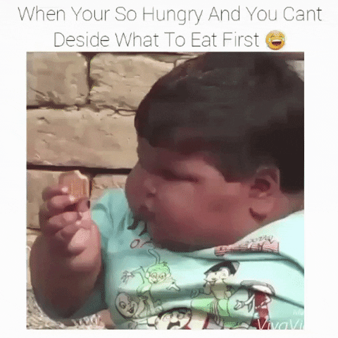 Video gif. A very chubby kid with big, round cheeks holds too many different cookies in each head. He looks at one and then another with a confused expression on his face. Text, “When you're so hungry and you can't decide what to eat first,” with a laughing crying emoji.