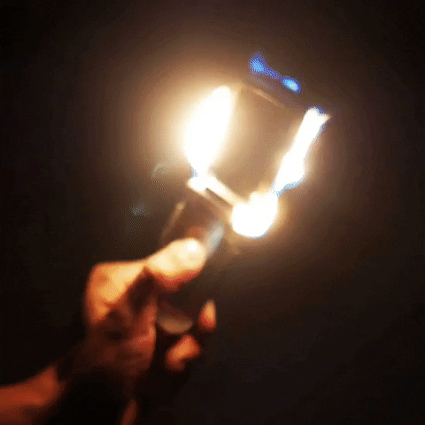 Video gif. Person presses buttons on a Razr cell phone while it's on fire.