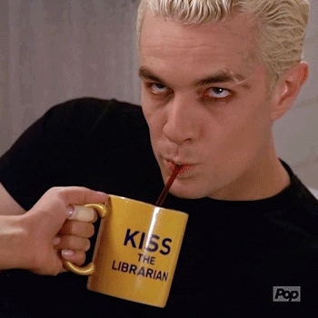 TV gif. James Marsters as Spike from Buffy the Vampire Slayer angrily drinks with a straw from a yellow mug that says "Kiss the Librarian". Someone else is clearly holding the mug, and that may or may not be coffee he's drinking.