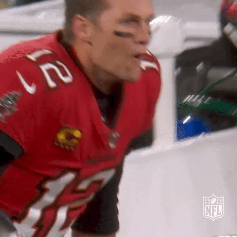 Sports gif. A celebrating Tom Brady of the Tampa Bay Buccaneers yells in excitement, then gives someone a high five.