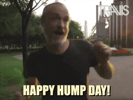 Celebrity gif. In front of a factory, singer Fran Healy smiles and dances around happily. Text, “Happy hump day!”