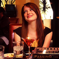 Movie gif. Emma Stone as Hannah in Crazy, Stupid, Love sits at a table in a restaurant, smiling and blushing as she turns away with a touch of embarrassment.