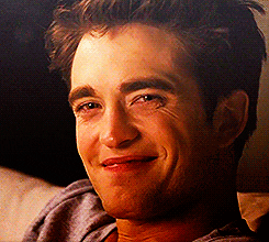 Movie gif. Robert Pattinson as Edward in Twilight. He's sitting on a couch and slowly laughs, building up to a full toothed chuckle.