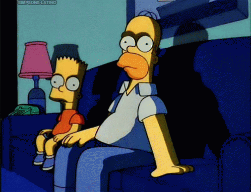 Bart and Homer Simpson with blank stares, sitting on a couch and in darkness, with Homer patting the empty seat next to him in anticipation