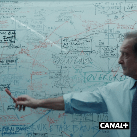 TV gif. Vincent Lindon as Simon Weynachter in Dargent et des Enfants stands in front of a whiteboard filled with words and scribbles. He holds a red marker in his hand as he points to one of the words.