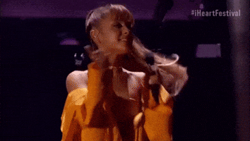 Celebrity gif. Ariana Grande blows a kiss and waves to the audience after performing at the 2016 iHeartRadio Music Festival.