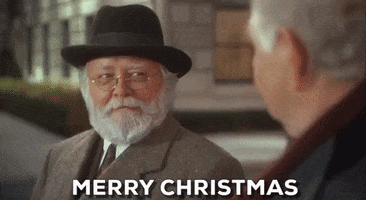 Movie gif. Richard Attenborough as Kris Kringle in Miracle on 34th Street touches the brim of his cap and smiles while saying "Merry Christmas," which appears as text.