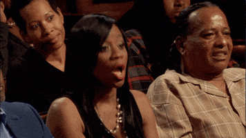 TV gif. A woman seated in an audience drops her jaw and throws her hands up in shocked surprise. 