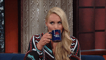 TV gif. Skier Lindsey Vonn shifts her eyes back and forth suspiciously as she sips from a mug on The Late Show with Stephen Colbert.