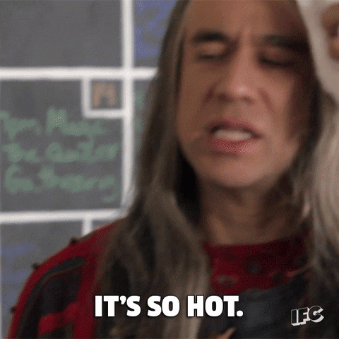 TV gif. Comedian Fred Armisen from Portlandia dressed as Candace in a long wig dabs his forehead with a cloth as he perspires and complains "It's too hot!". The camera pans to comedian Carrie Brownstein as Toni who offers the explanation "it's the heat."