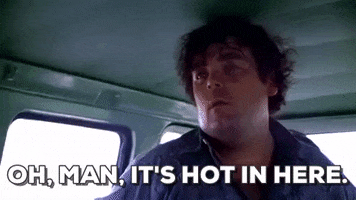 Movie gif. Paul A. Partain as Franklin in the Texas Chainsaw Massacre sits inside a vehicle, looking frustrated and overheated, brushing his hair from his forehead as he says, "oh, man, it's hot in here," which appears as text.