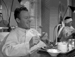 Movie gif. Dennis Morgan as Jefferson in the classic black and white film Christmas in Connecticut happily tucks into a meal while sitting in a hospital bed. He closes his eyes and tips his head back in ecstasy, reveling in the delicious bite.