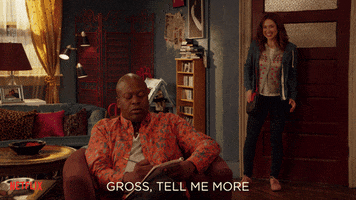 TV gif. Tituss Burgess as Titus and Ellie Kemper as Kimmy on Unbreakable Kimmy Schmidt. Kimmy stands in the doorway looking giddy with news and Titus sits in a chair writing in a journal and doesn't stop writing as he says, "Gross. Tell me more."