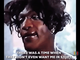 Video gif. Marsha P Johnson raises her eyebrows and speaks sincerely. Text, "There was a time when they didn't even want me in stuff."