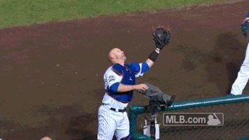 Sports gif. Chicago Cubs catcher David Ross attempts to catch a ball, but fumbles. Teammate Anthony Rizzo swoops in and catches it before it hits the ground.