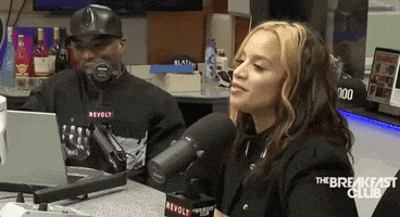 Celebrity gif. Dascha Polanco sits for an interview alongside a man, both with microphones. With a slight smirk, she nods her head and appears to say, "Yes."