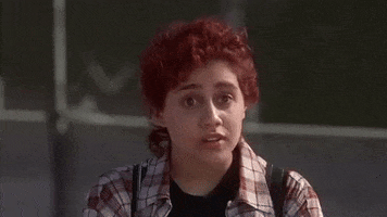 Movie gif. Brittany Murphy as Tai in Clueless presses her hand to her heart and looks honored.
