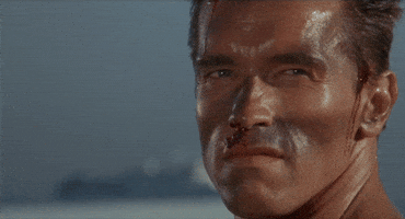 Movie gif. The bloody and beat-up face of Arnold Schwarzenegger as John Matrix in Commando, looking out and saying, "no chance."
