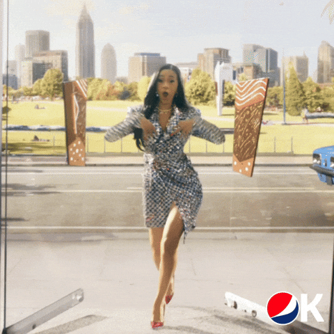 Ad gif. Cardi B in the Pepsi Super Bowl Commercial pushes open two glass doors and struts in as she says, “Okurrrr.” and then sticks her tongue straight out.