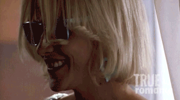 Movie gif. Patricia Arquette as Alabama Whitman in True Romance wears sunglasses and smiles. She smokes a cigarette very quickly and then pulls it out of her mouth to smile at us directly.