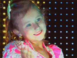 TV gif. A little girl in a beautiful pageant gown spreads her arms on stage in a delicate gesture. 