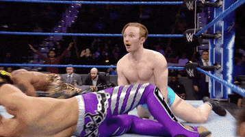 Sports gif. Dramatic zoom on Gentleman Jack Gallagher in the WWE ring looking stunned as other wrestlers fight in front of him.