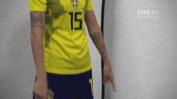 Video gif. Soccer player Nathalie Bjorn stretches out both arms pointing her index fingers at something off screen with a calm and pleasant expression on her face. 