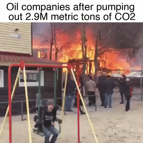 Video gif. Child swings joyfully on a swing set while a building fire rages in the background. Caption, “Oil companies after pumping out 2.9 metric tons of CO2.”