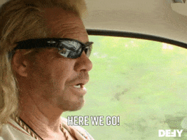 Reality TV gif. Duane Chapman in Dog the Bounty Hunter wears sunglasses as he drives down a tree-lined road and says, "Here we go!"