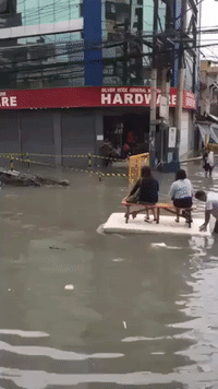 Manila Residents Ride on Makeshift Rafts in Flooded Street