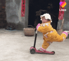 Video gif. A toddler in yellow grins as they ride a scooter. Their leg sticks out behind them as they speed away.