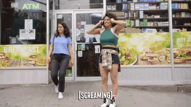 An animated gif video clip from the TV show Broad City. Twho young woman down a sidewalk and one of them stops and starts primal screaming in a crouch. The other turns to see what is going on and we zoom in on the screaming face.
