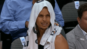 Sports gif. Steph Curry has a towel over his head as he looks from the bench to the court with confusion and disbelief.